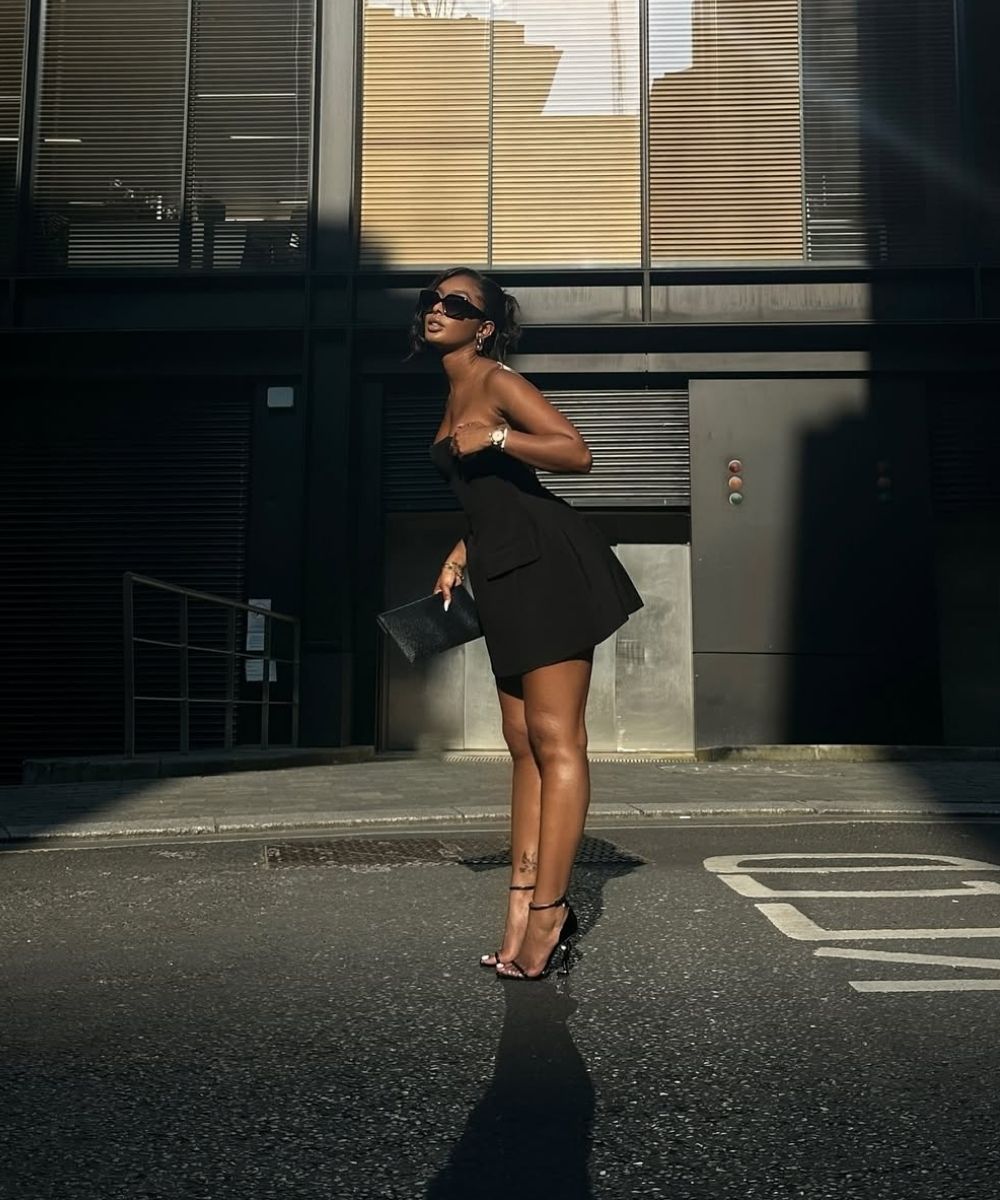 Woman in a black dress standing on a street with a building in the background