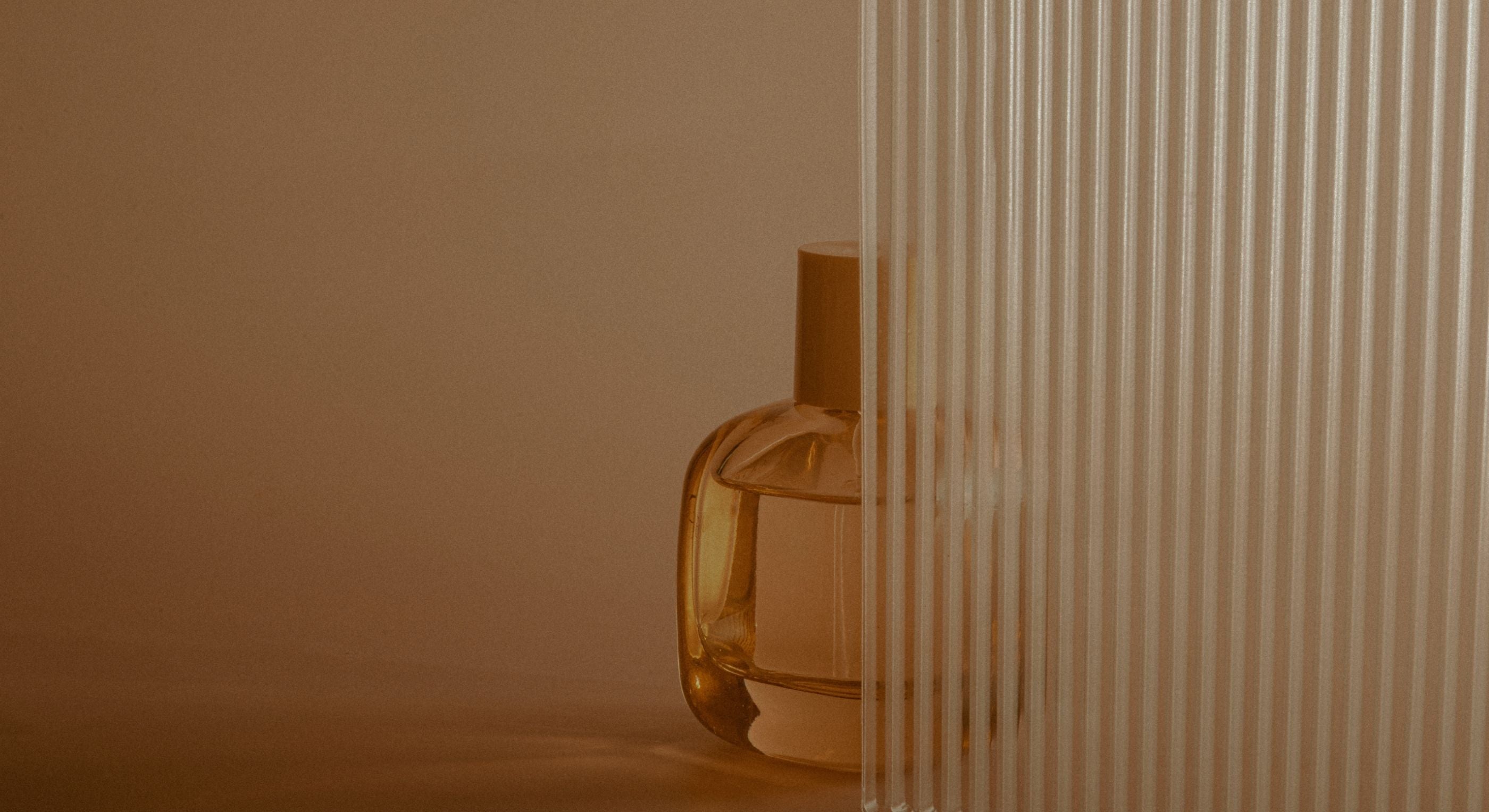 Amber glass perfume bottle against a beige background