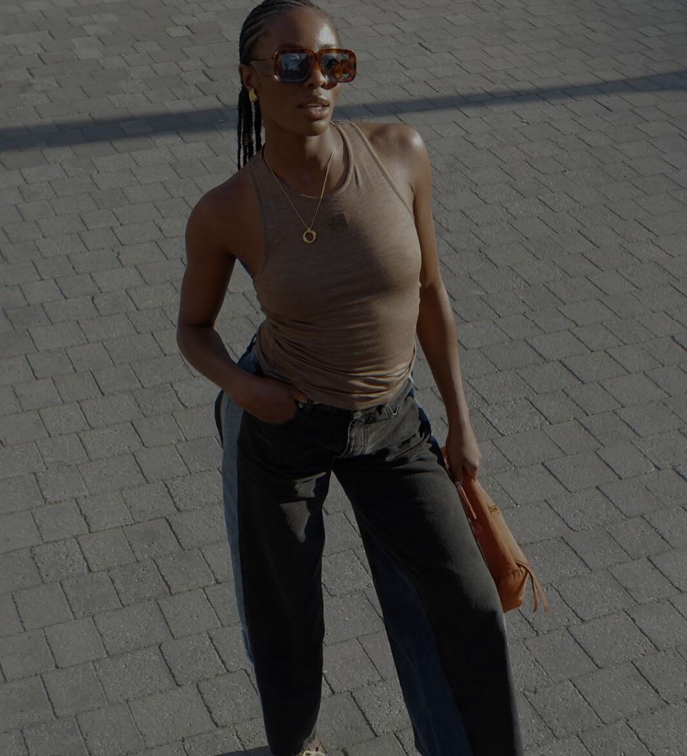 Woman walking on a paved road wearing sunglasses and casual clothing