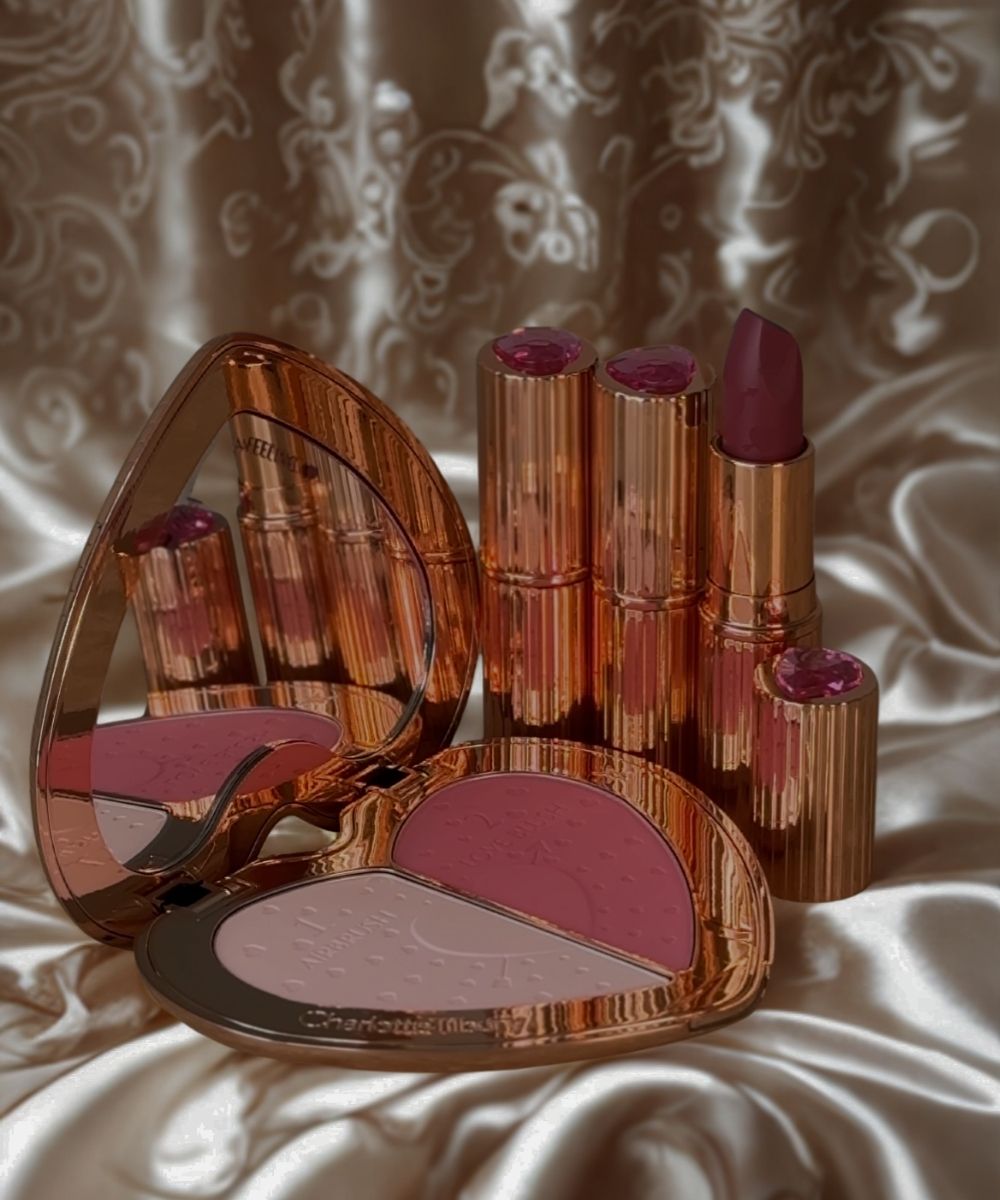 Makeup set with lipsticks, blush, and compact on a textured fabric background