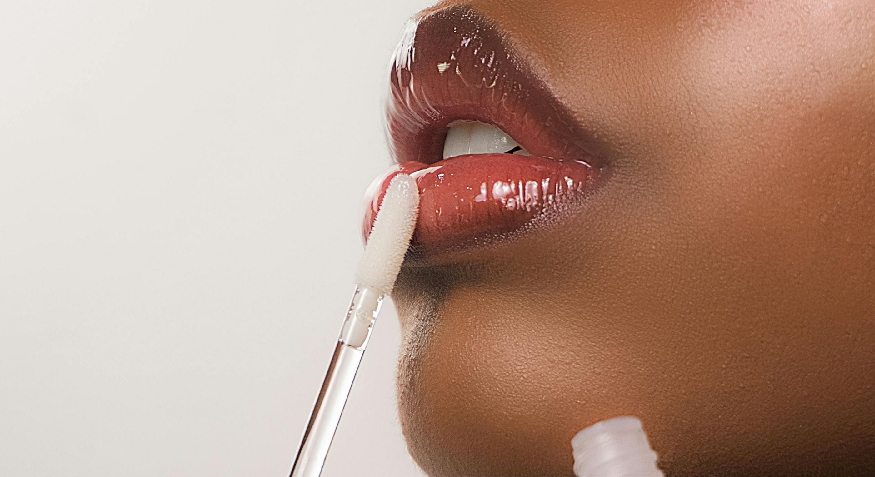 Close-up of a person applying lip balm with a applicator on a neutral background