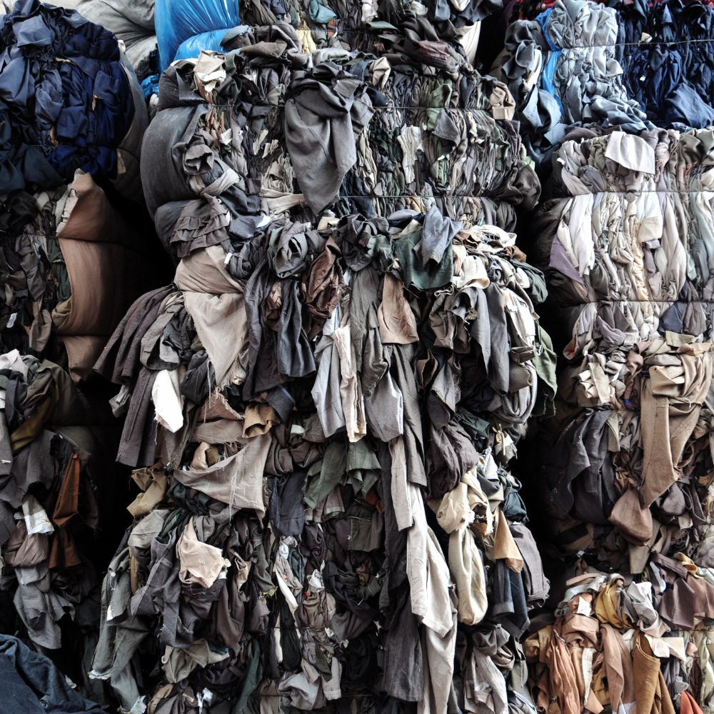 Stack of assorted used clothing items in various colors.